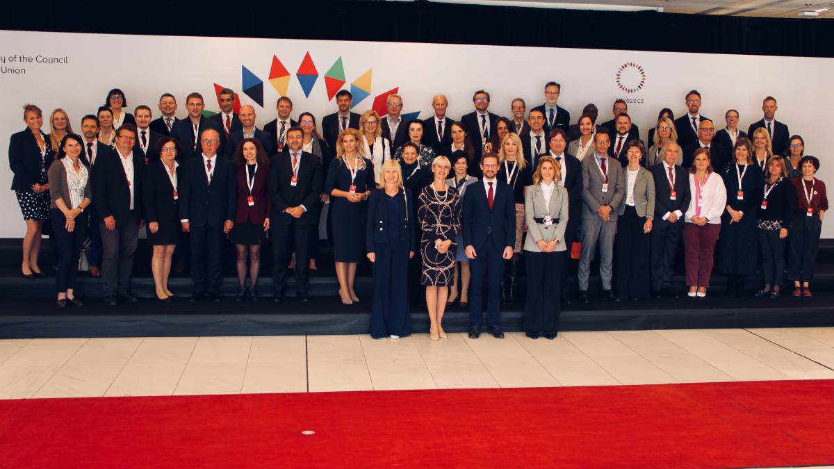 Na zdjęciu widoczni stojący kobiety i mężczyźni, po prawej stronie widoczny częściowo znaczek EU2022CZ