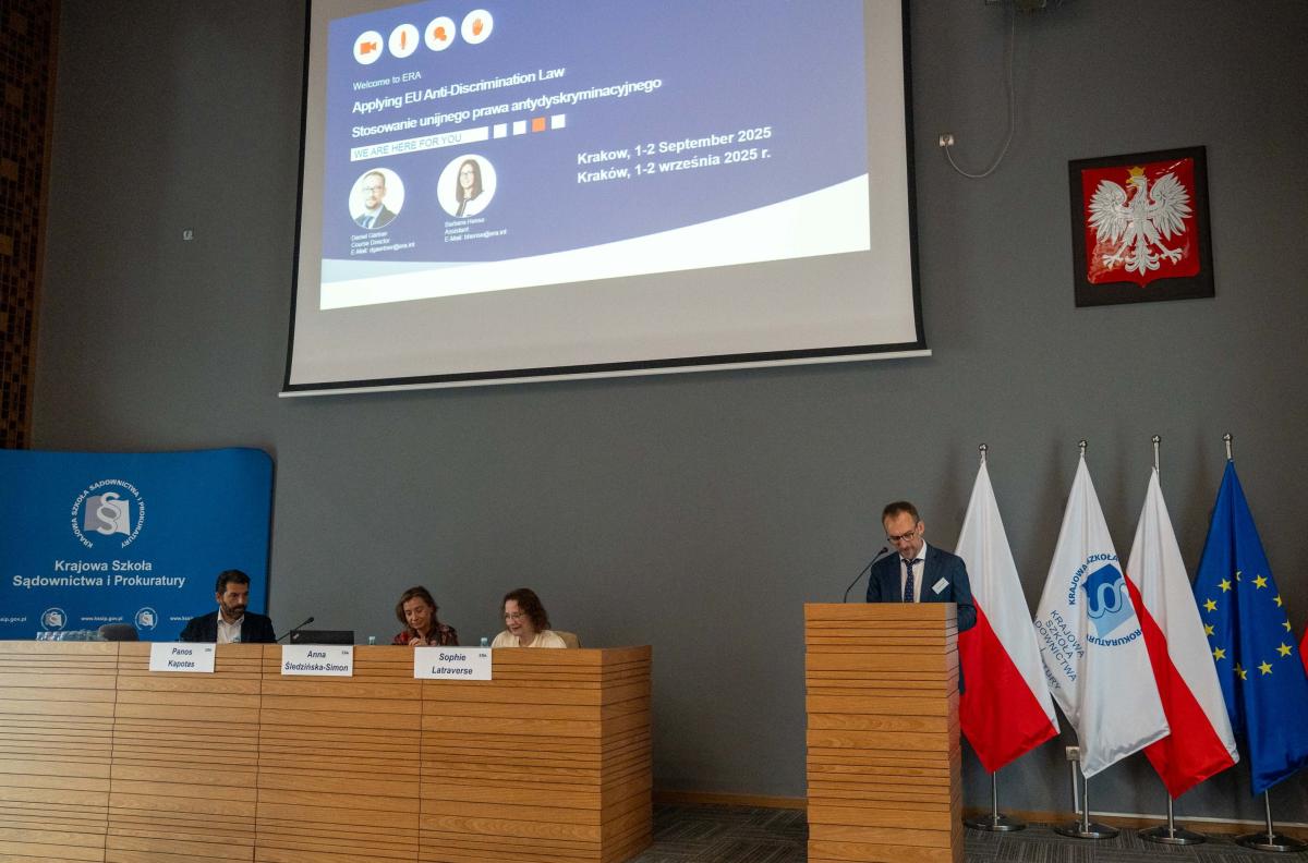  Daniel Gaertner z Akademii Prawa Europejskiego wita z mównicy uczestników konferencji. Przy stole prezydialnym od prawej wykładowcy: Sophie Latraverse, Anna Śledzińska-Simon, Panos Kapotas.