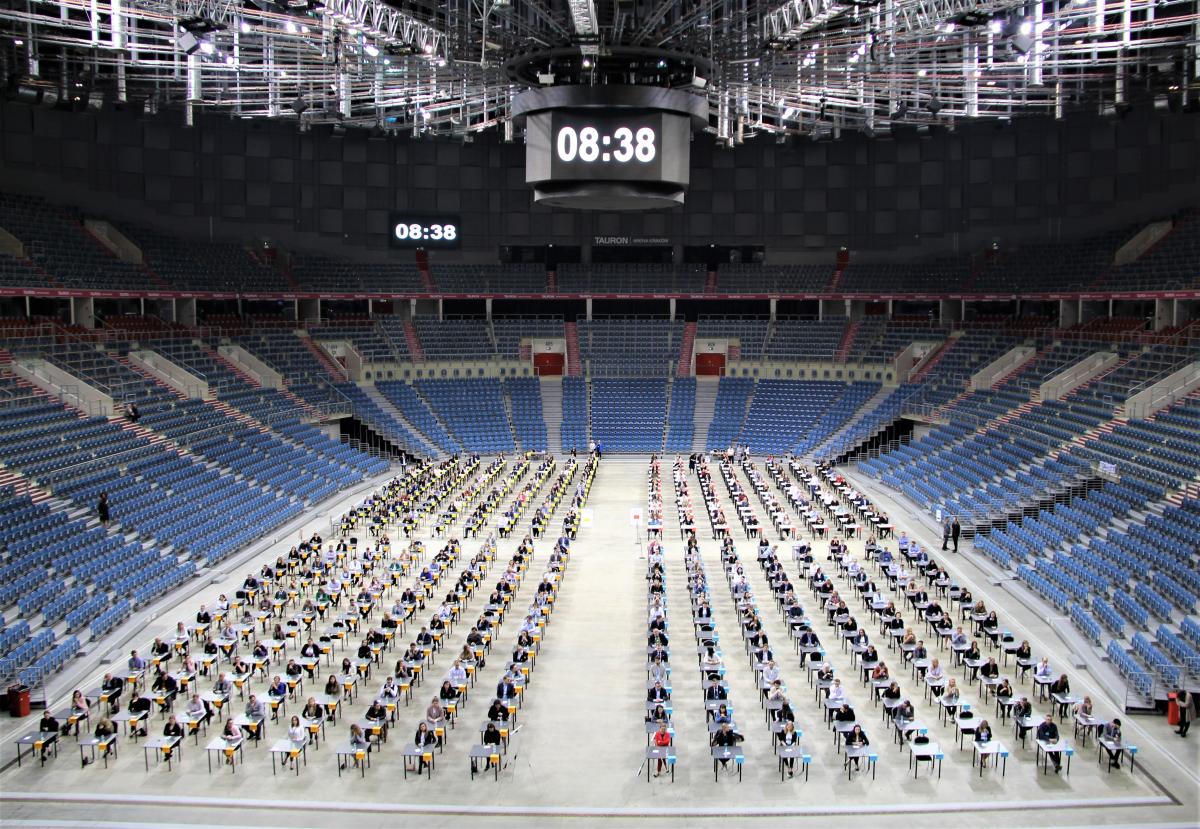 na zdjęciu widać salę na której kandydaci, którzy przybyli na konkurs siedzą przy swoich stolikach i czekają na rozpoczęcie egzaminu