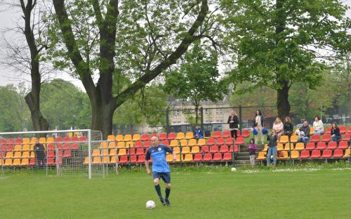 Zdjęcie nr 8: jeden mężczyzna biegnący z piłką do piłki nożnej na boisku oraz kibice na trybunach