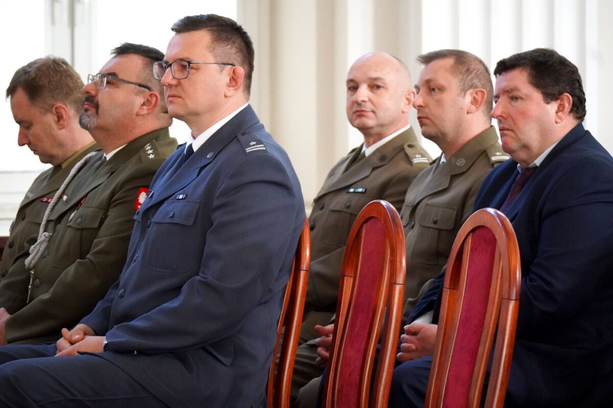 Na zdjęciu widoczna sala konferencyjna, widocznych pięciu mężczyzn w mundurach, jeden mężczyzna w garniturze. Widoczne dwa puste krzesła