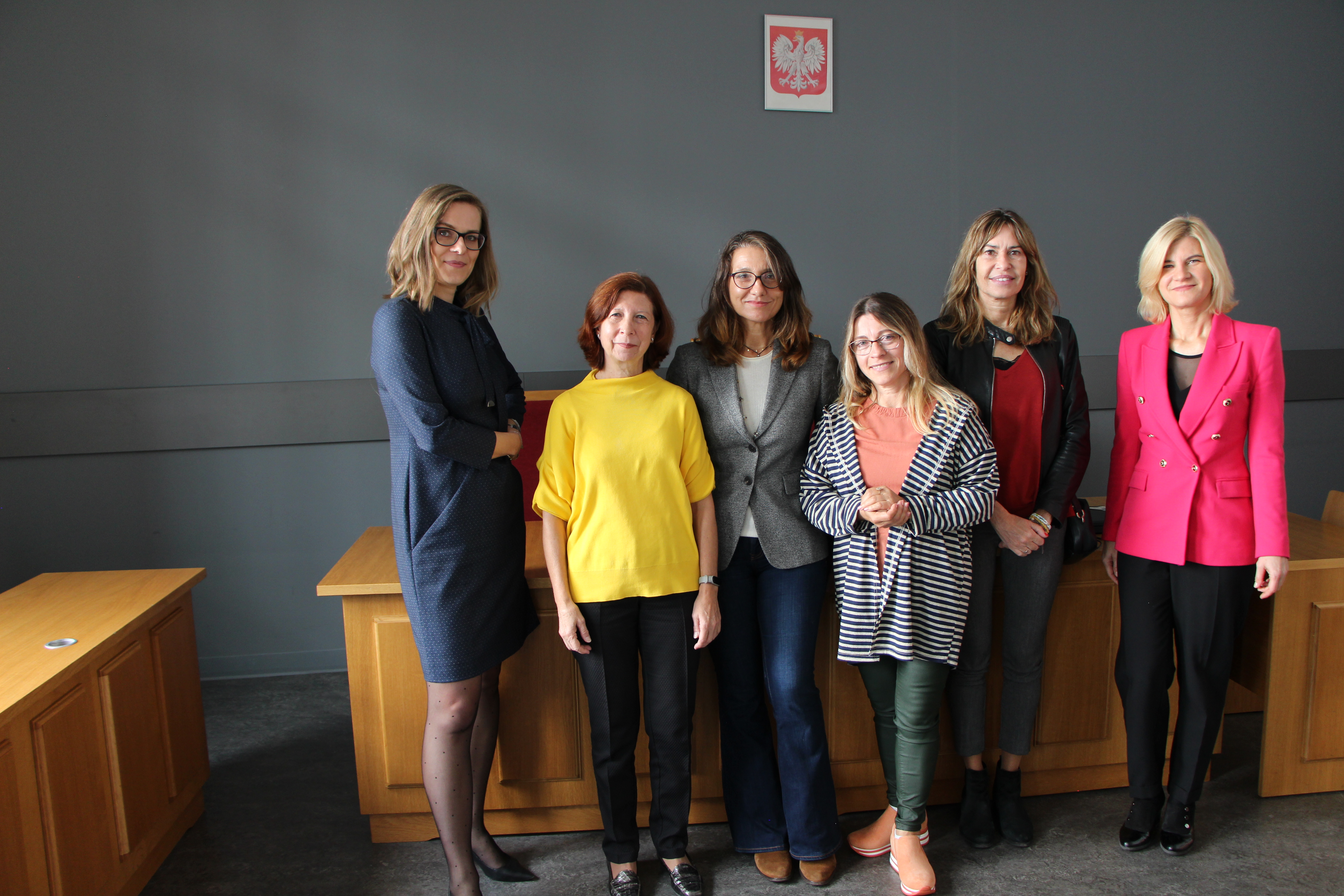 6 kobiet stojących na tle ściany z godłem Polski