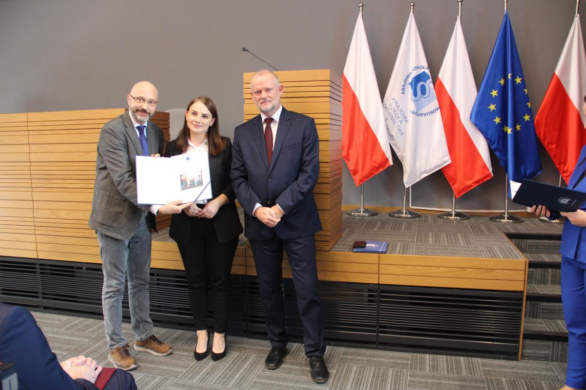 Dyrektor KSSiP wraz z Zastępcą Dyrektora kierującym Ośrodkiem Aplikacji Prokuratorskiej wręczają dyplom zwyciężczyni XIV edycji Konkursu Krasomówczego