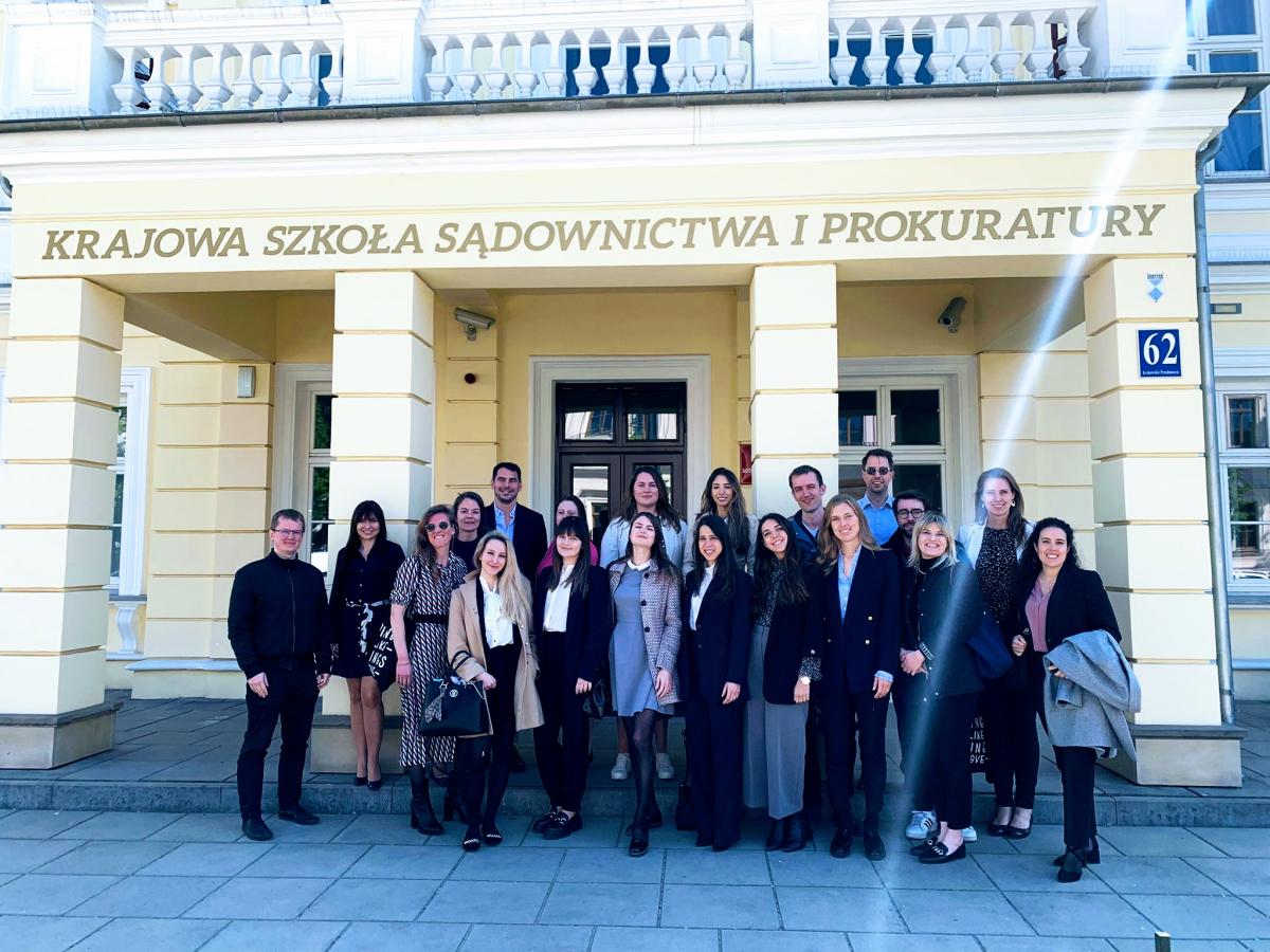 Uczestnicy wydarzenia pozują do grupowego zdjęcia stoją przed głównym wejściem do siedziby Krajowej Szkoły Sądownictwa i Prokuratury w Lublinie